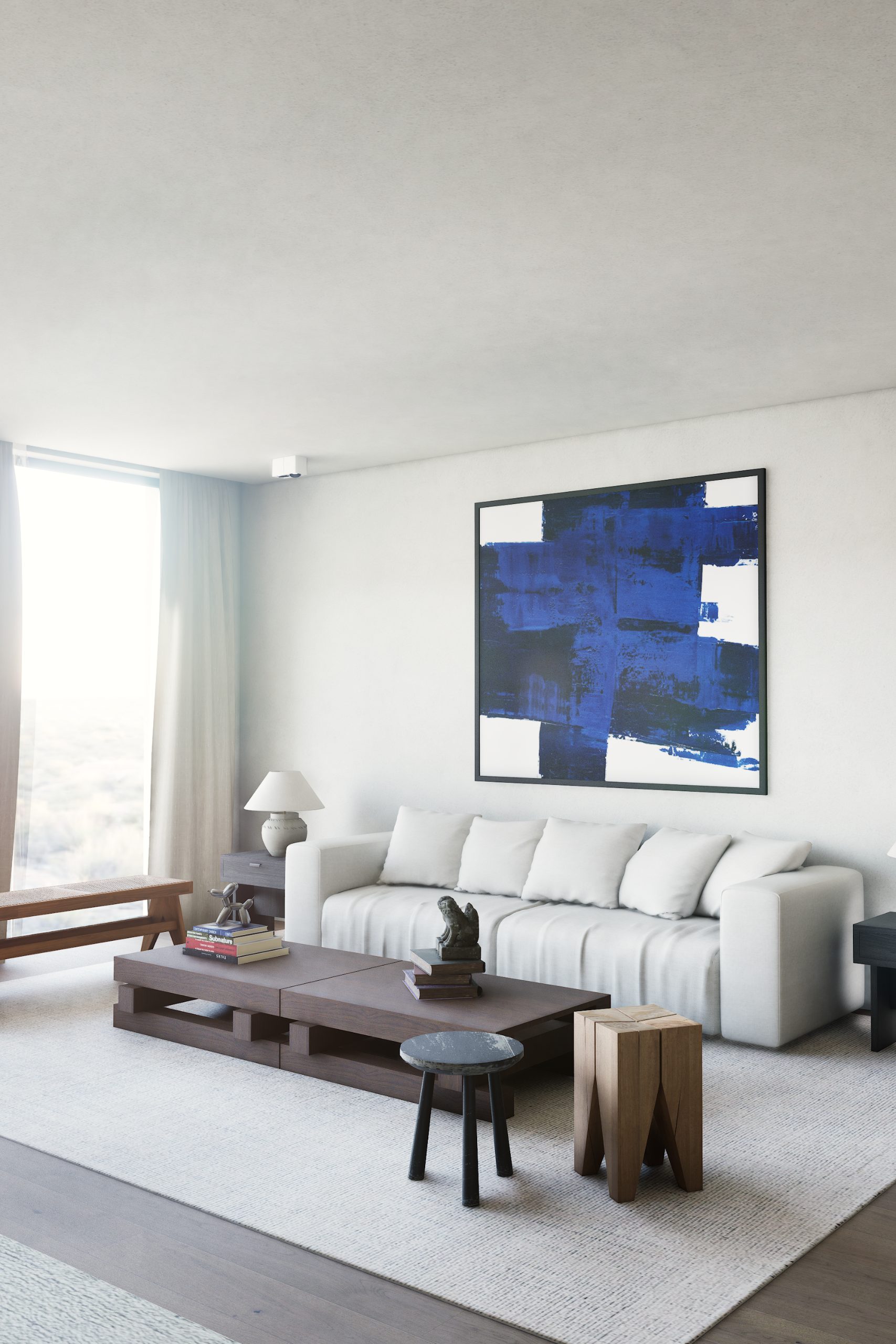 Zithoek schuin van opzij, blauw schilderij boven de bank en licht van het raam